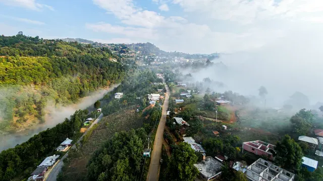 Vista aérea del municipio cubierto parcialmente por niebla, con vegetación densa alrededor.